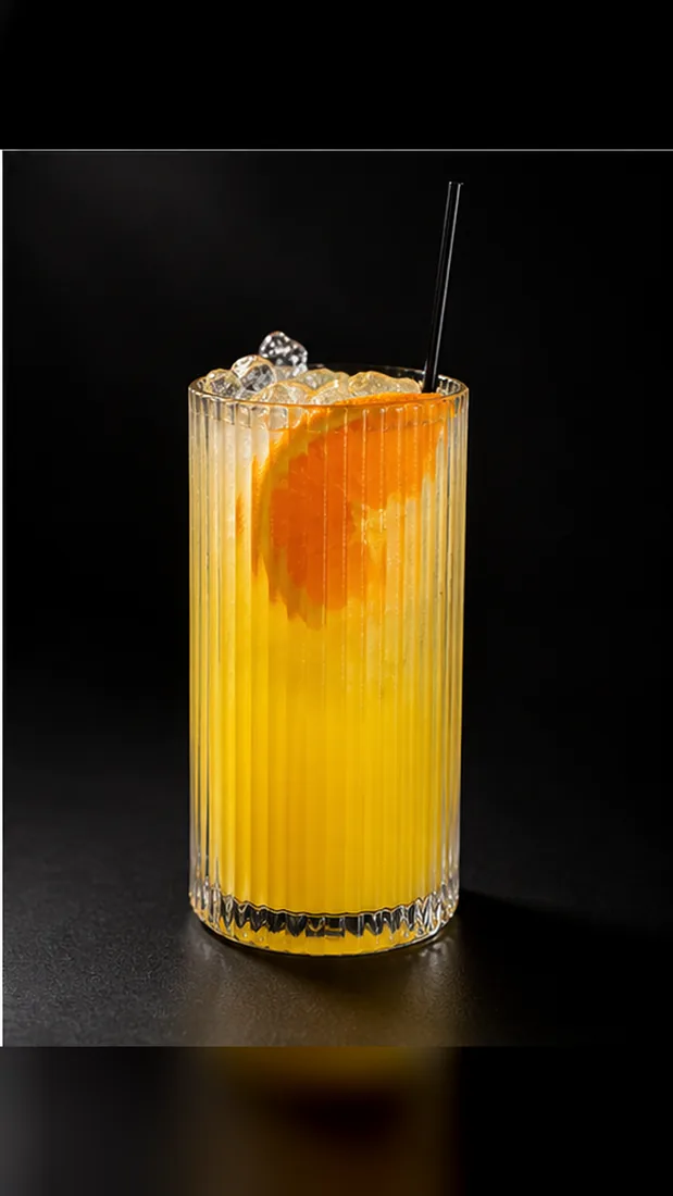A mimosa in a tall ribbed glass with an orange wheel